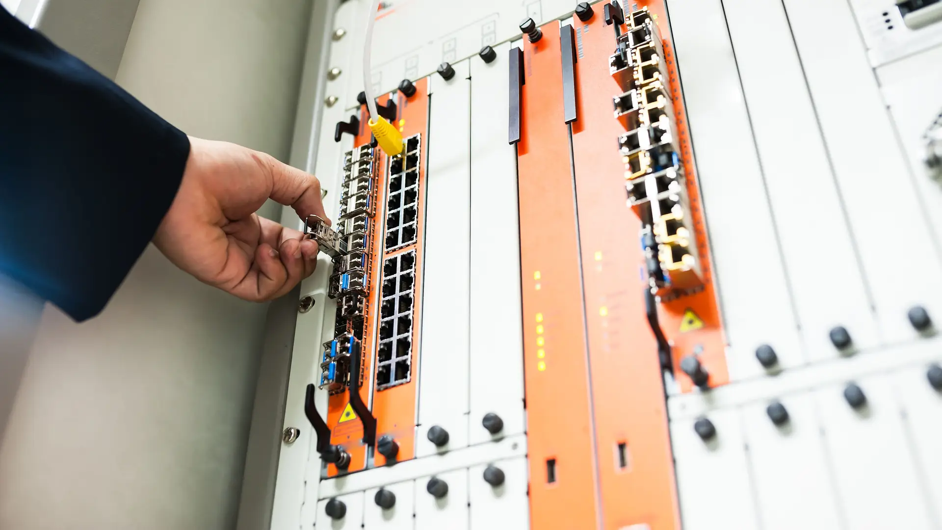 A technician’s hand fitting a module into a network switch in a bright server room