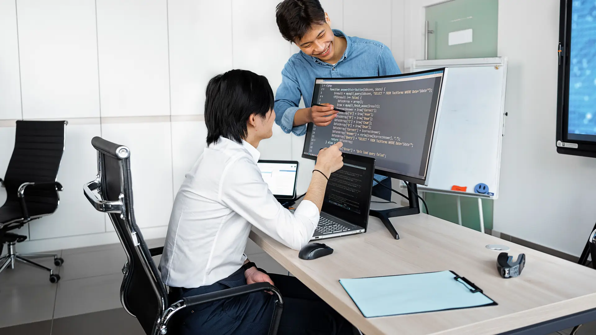 Two software engineers reviewing code together at a monitor